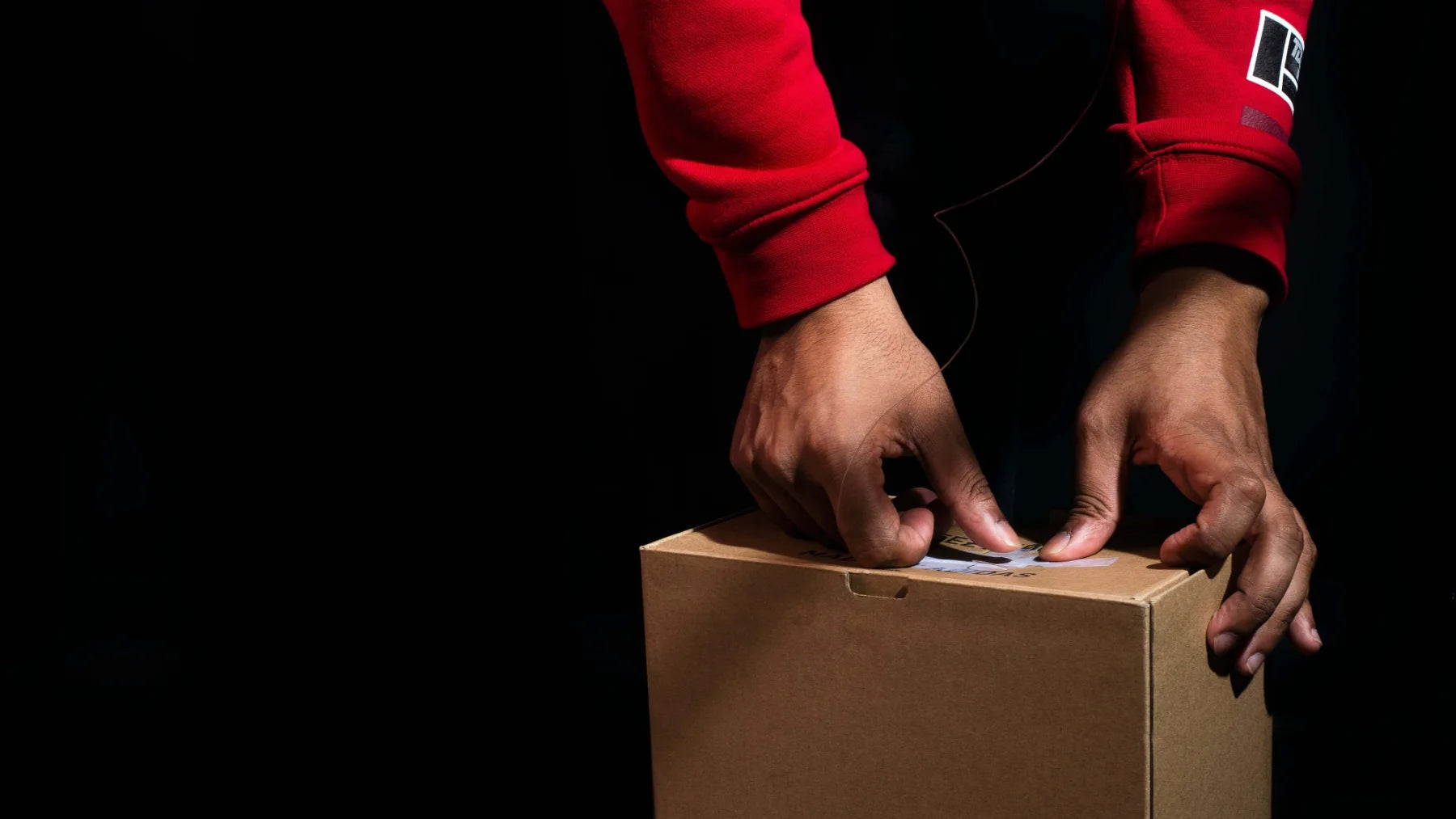 Photo of hands packing a box in red jacket